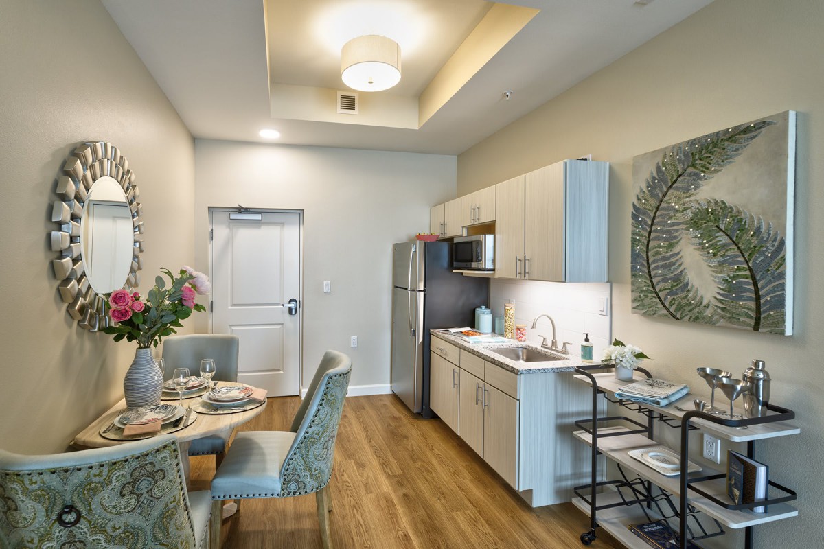 A modern apartment kitchen and dining area with elegant decor and wood flooring.
