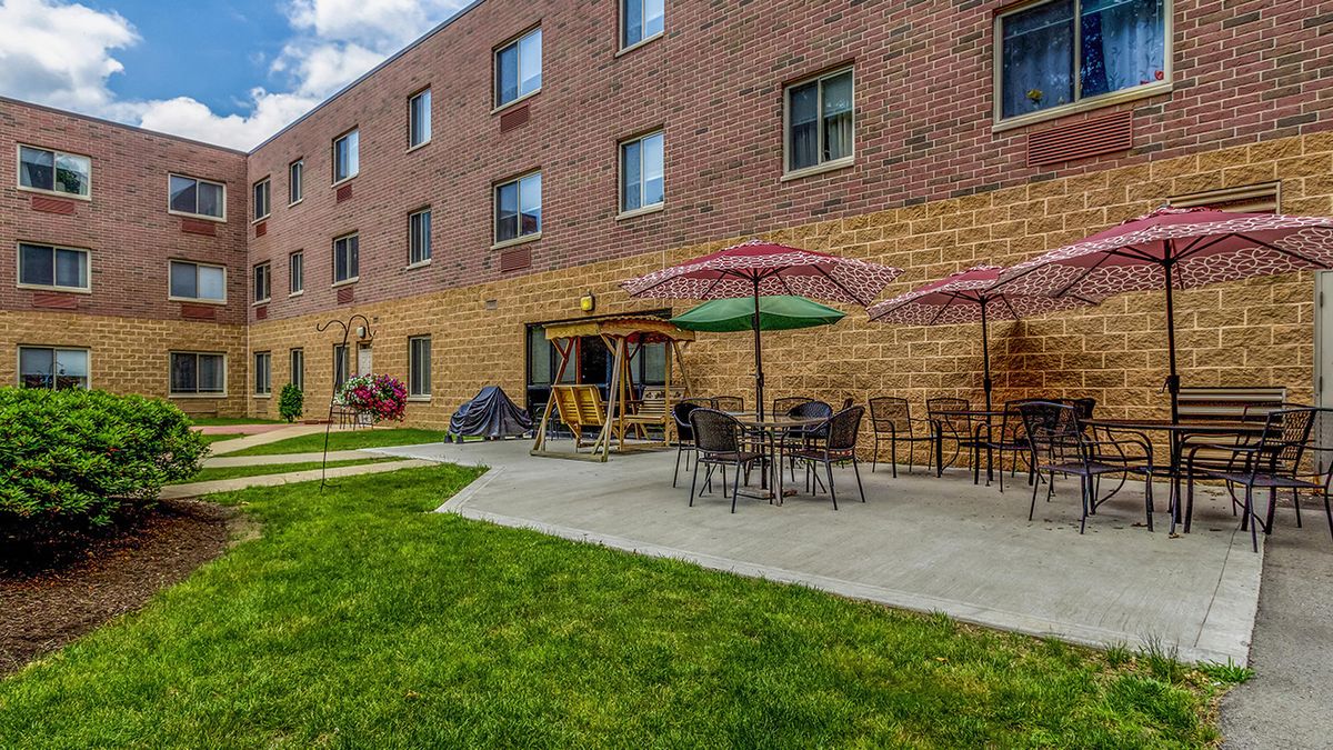 Outdoor patio area with tables and colorful umbrellas next to a brick building.