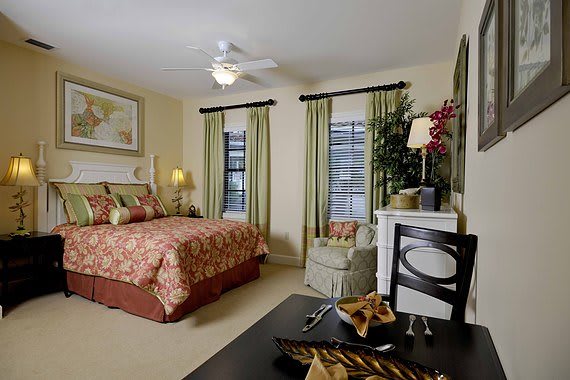 A cozy bedroom interior with a well-decorated bed, green curtains, and elegant furnishings.