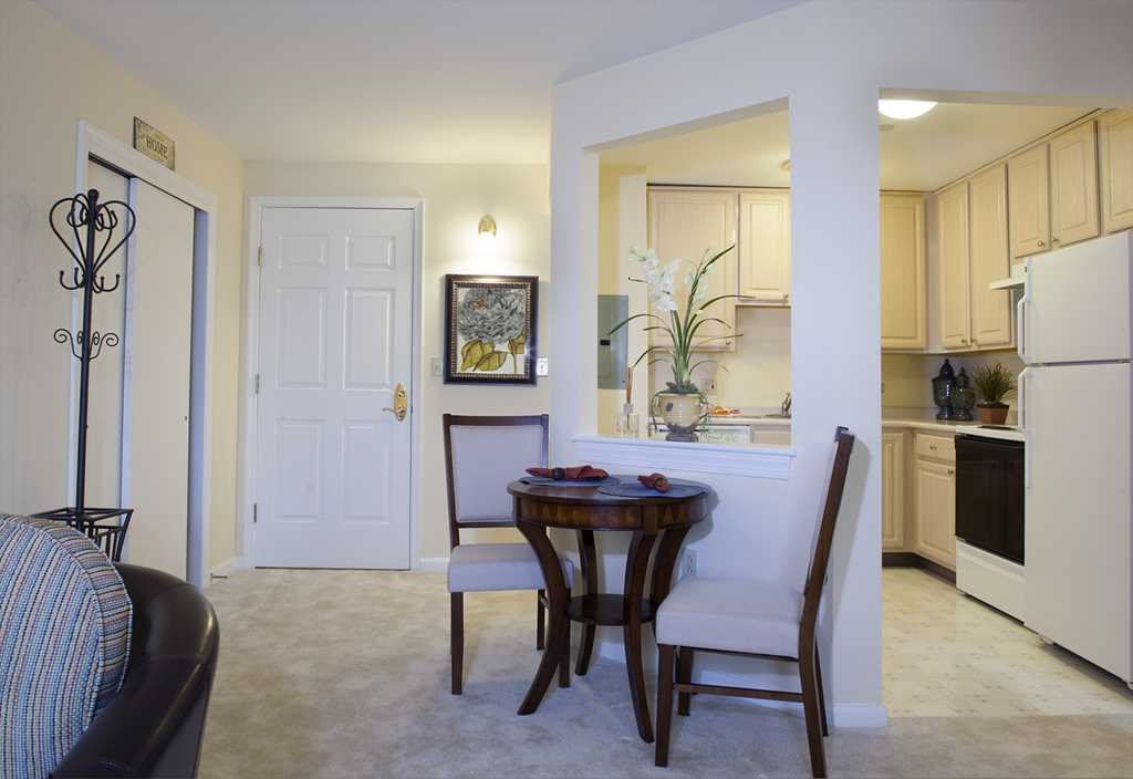 A cozy living space with a small dining table, chairs, and an open view into the kitchen.