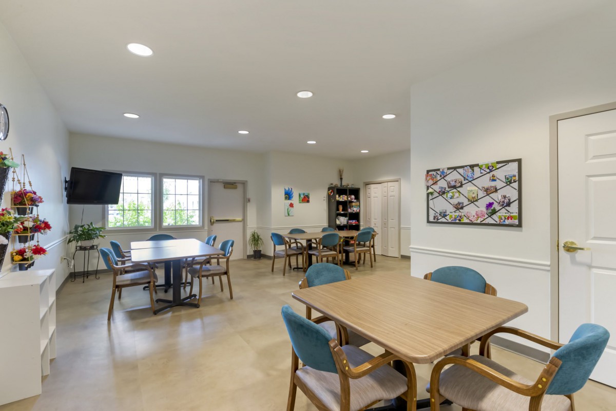 A spacious and well-lit meeting room featuring tables, chairs, and decorative artwork on the wall.