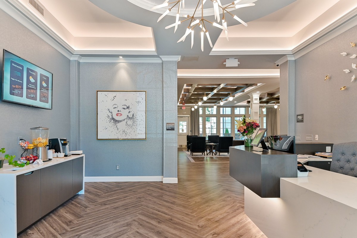 A stylish and modern reception area featuring a unique chandelier, contemporary artwork, and warm wood flooring.
