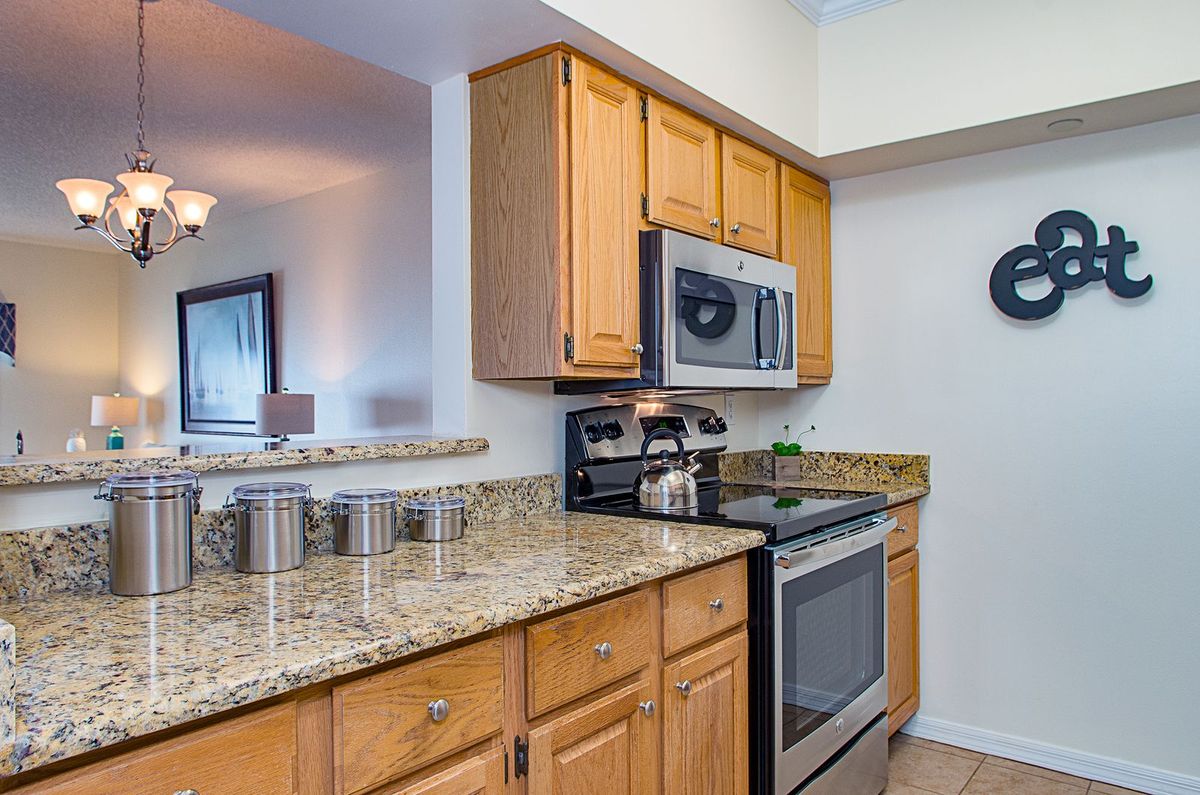 A modern kitchen featuring wood cabinets, granite countertops, and stainless steel appliances.