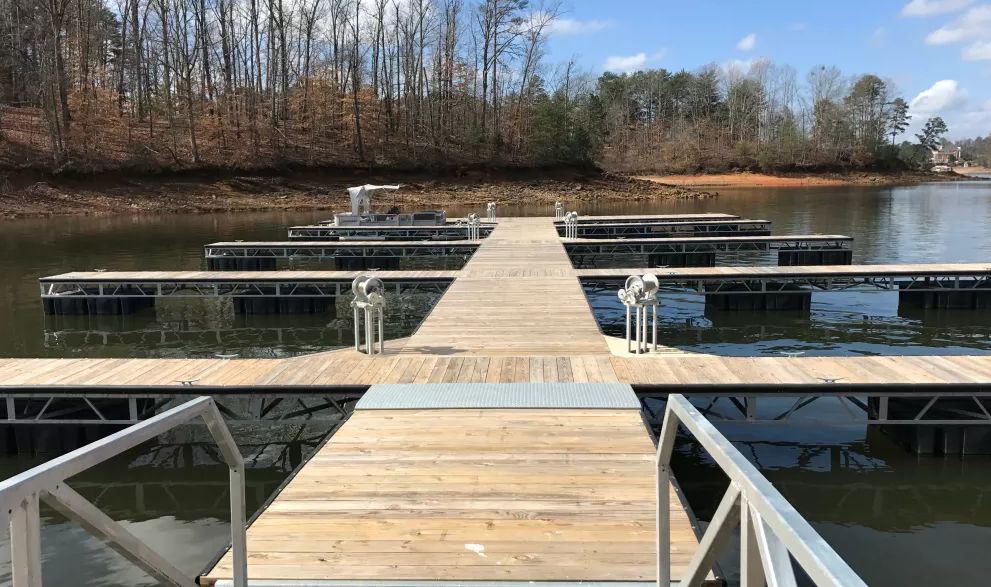 A wooden dock stretches over calm lake waters with boats moored on either side.