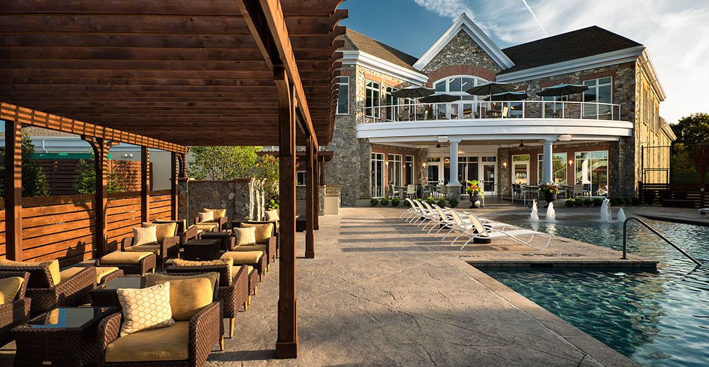 A luxurious home featuring a modern outdoor seating area, swimming pool, and spacious patio.