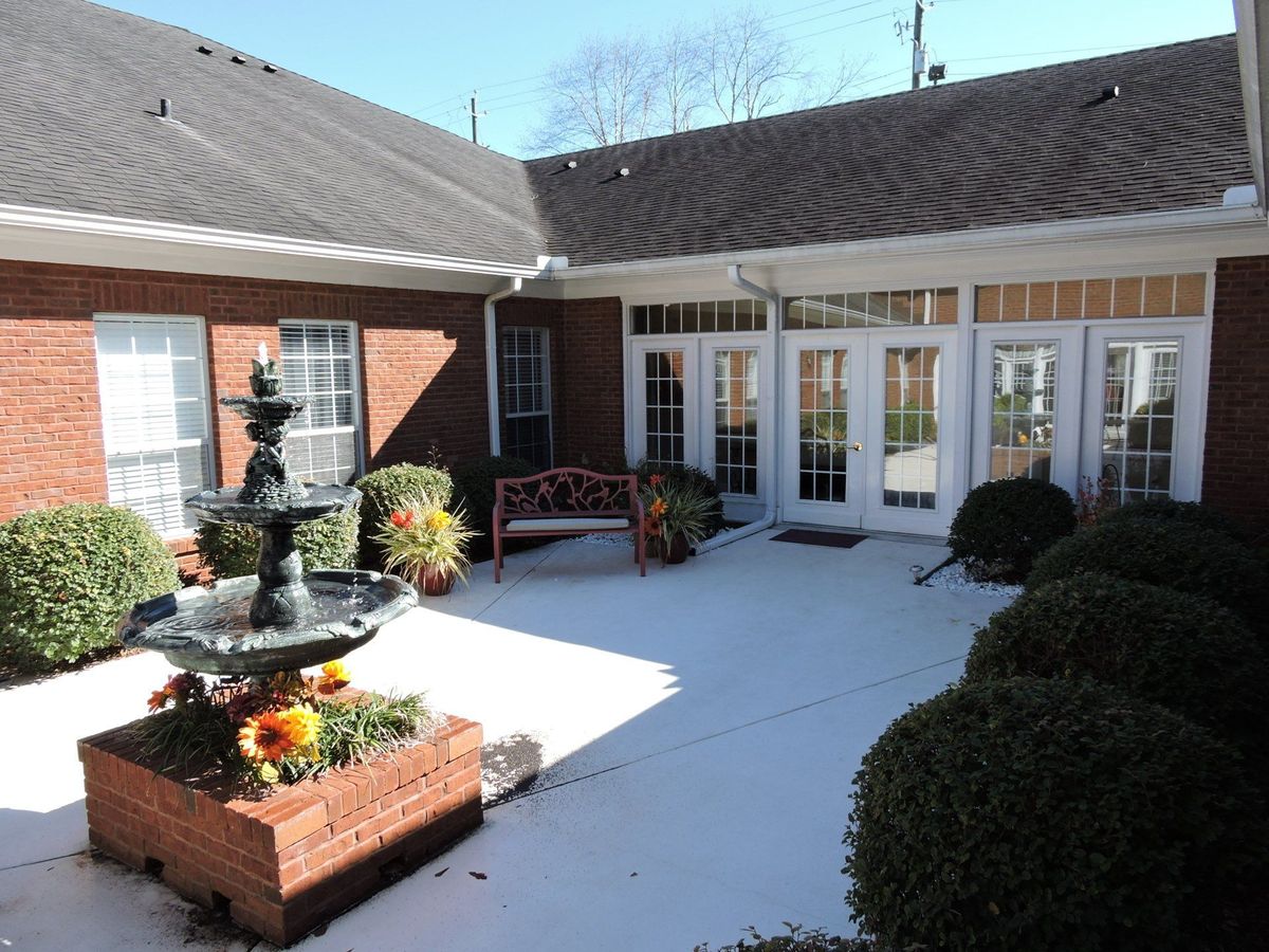 A serene courtyard featuring a fountain and outdoor seating surrounded by a brick building.