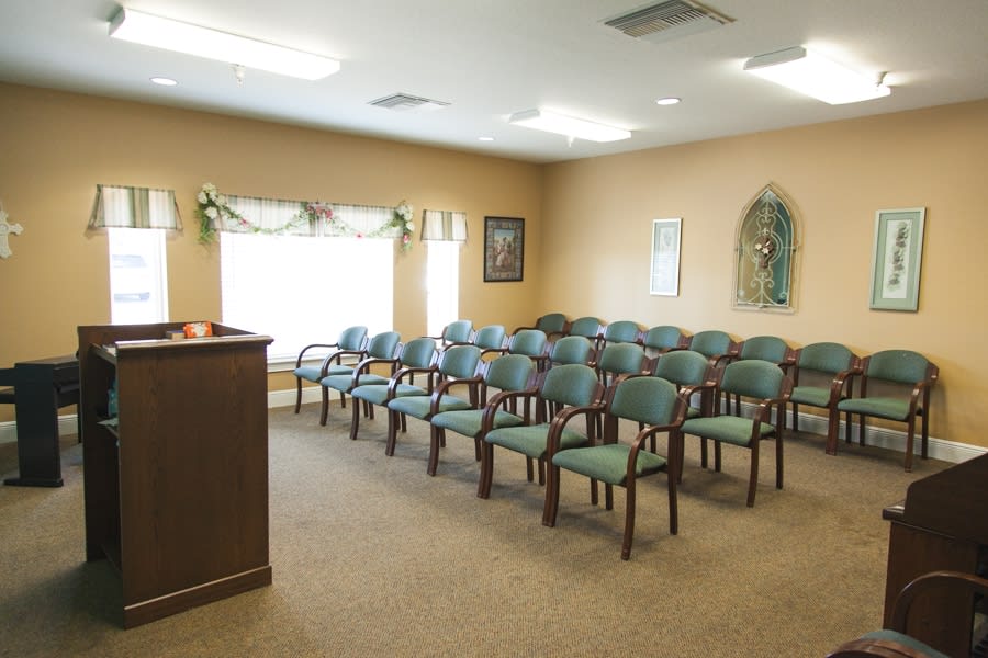An empty meeting room with rows of chairs and a podium.