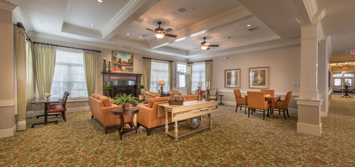 A cozy and elegant living room with comfortable sofas, a fireplace, and ceiling fans.