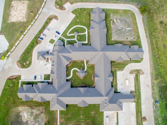 Aerial view of a large building complex with surrounding driveway and parking area.