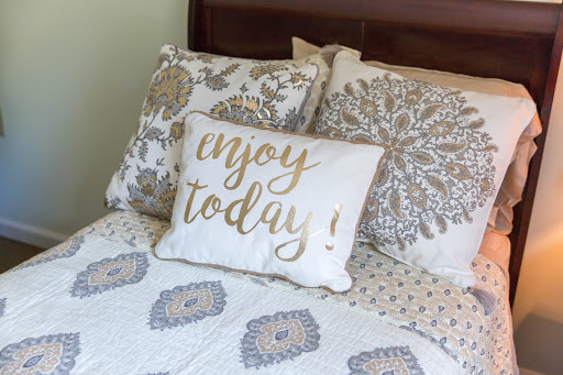 A cozy bedroom setting featuring a decorative pillow with an inspiring message.