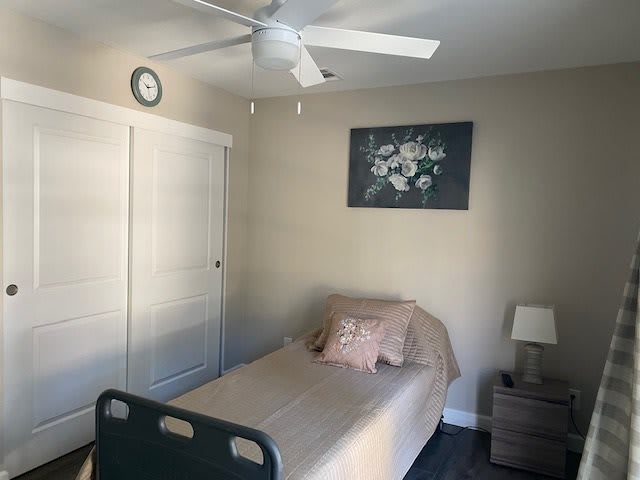 A minimalist bedroom featuring a single bed, a nightstand with a lamp, and a wall painting.