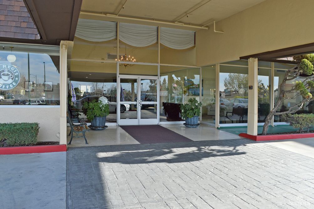 Entrance to a building with glass doors and potted plants.