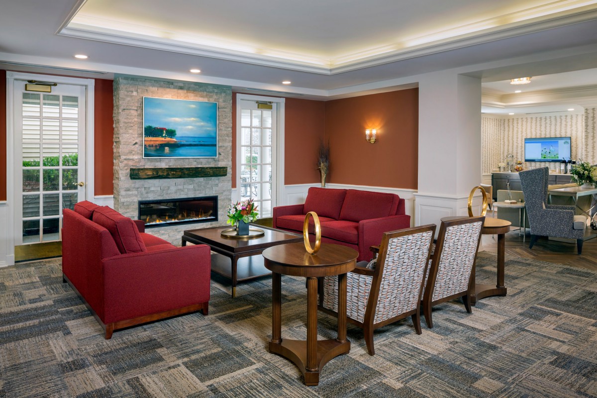 A cozy and stylish living room with red sofas, a fireplace, and modern artwork.