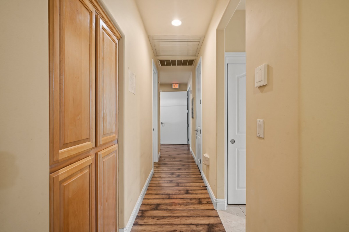 A well-lit hallway with wood flooring and cabinets along the wall.
