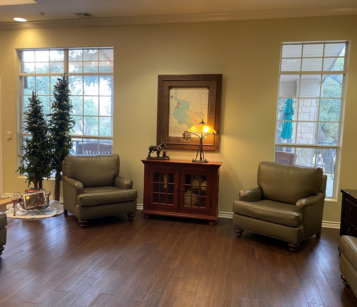 A cozy living room setup with two armchairs, a wooden cabinet, and decorative elements including a mirror and indoor plants.