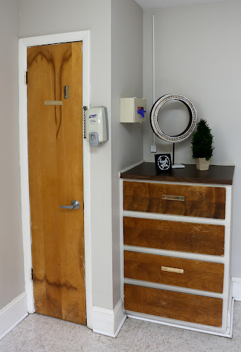 A stylish corner featuring a modern dresser, a round mirror, and a decorative plant.