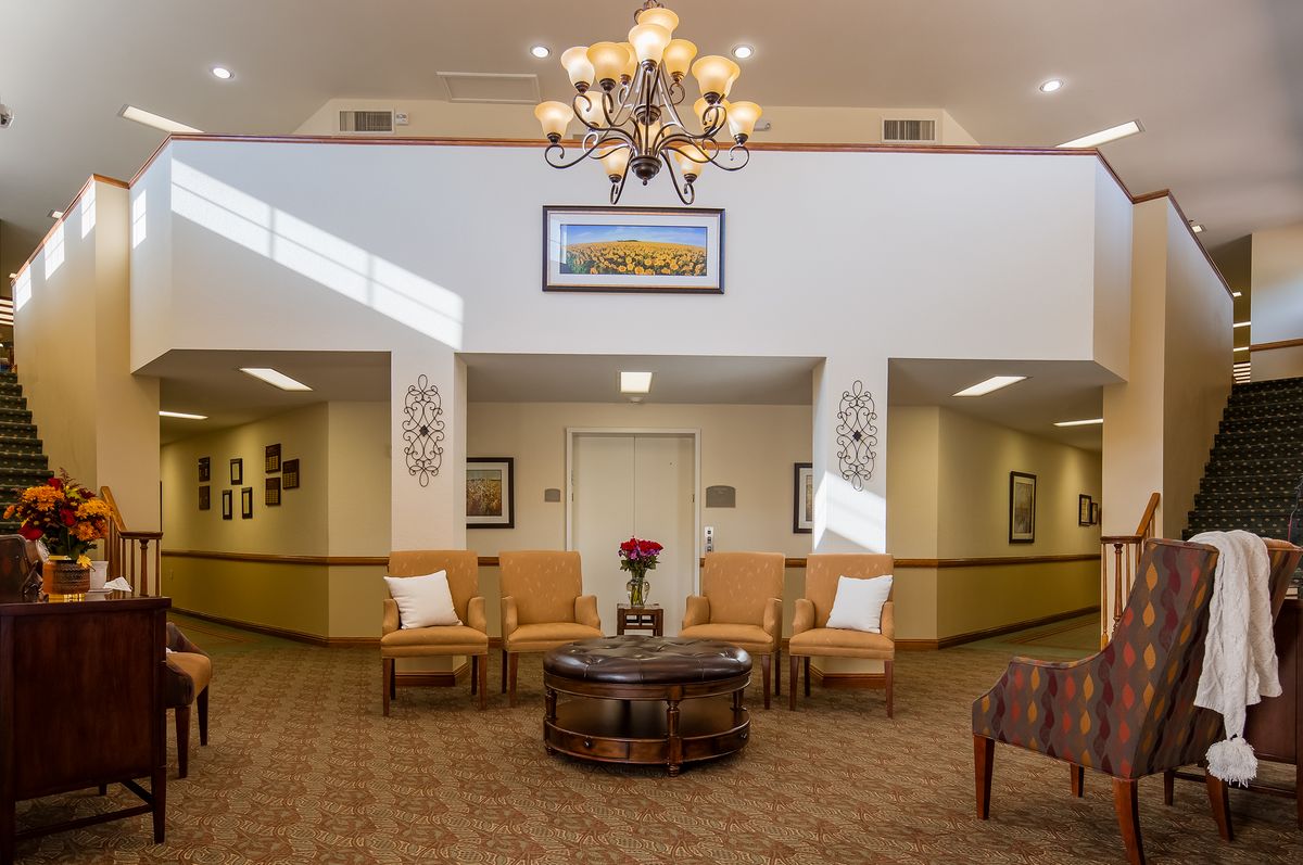 A well-lit lobby area featuring comfortable seating, a chandelier, and decorative artwork.