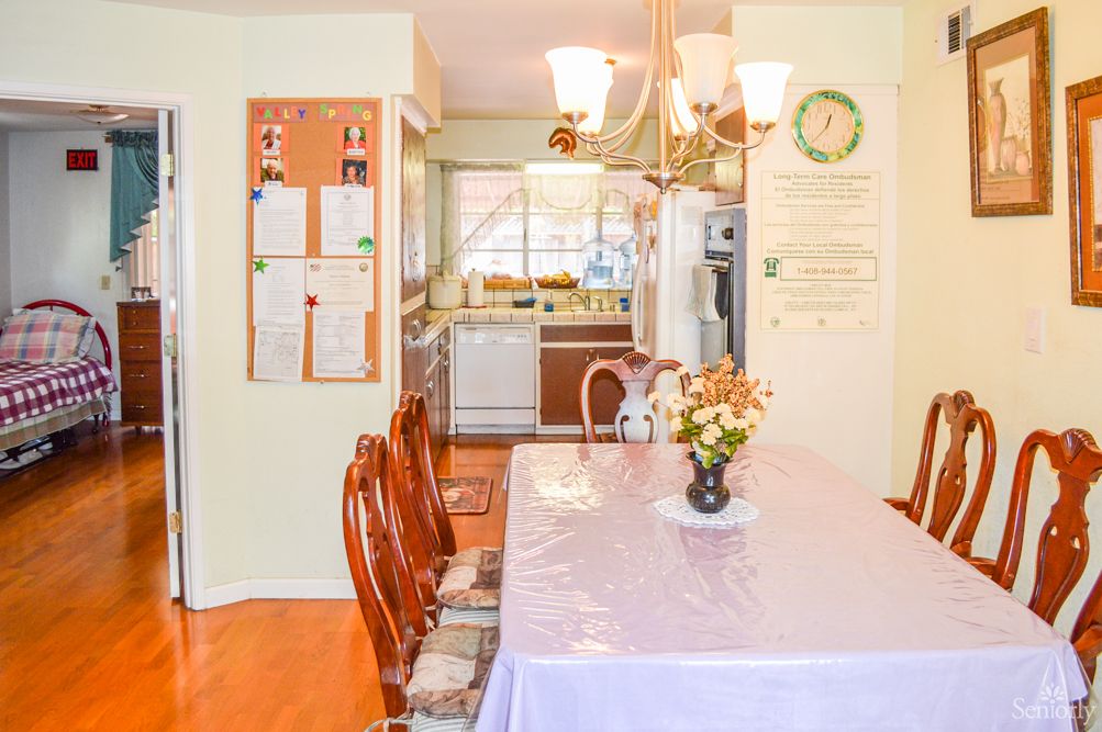 A cozy dining room with a table set for a meal, leading into the kitchen area.
