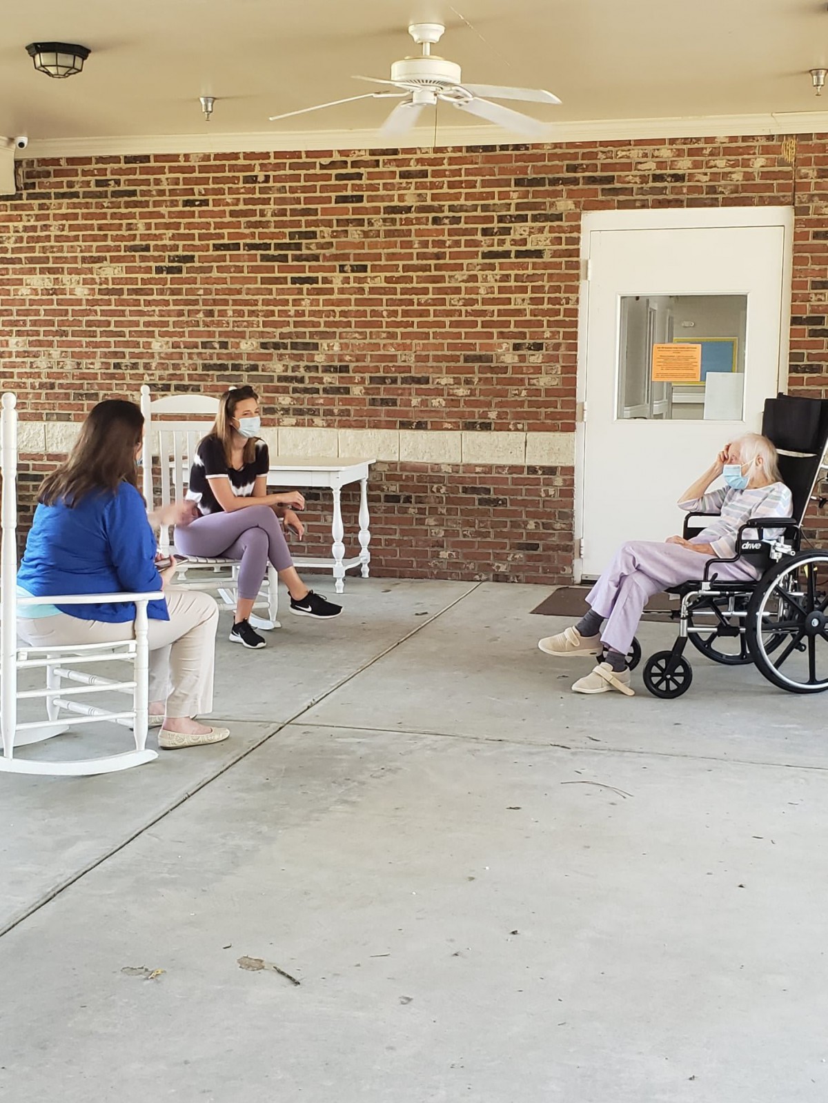 A group of people sitting outside a nursing home, engaging in conversation.