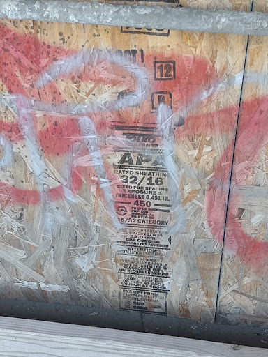 A weathered urban wall featuring graffiti and a faded poster.