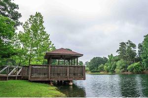 A serene gazebo overlooking a tranquil lake surrounded by lush greenery.
