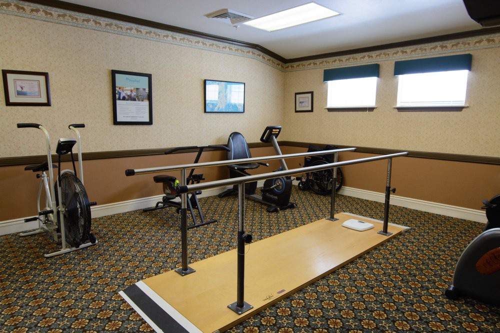 A rehabilitation room equipped with parallel bars and exercise machines.