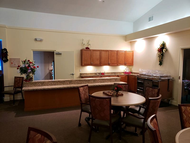 A cozy kitchen and dining area with wooden cabinets and a round table surrounded by chairs.