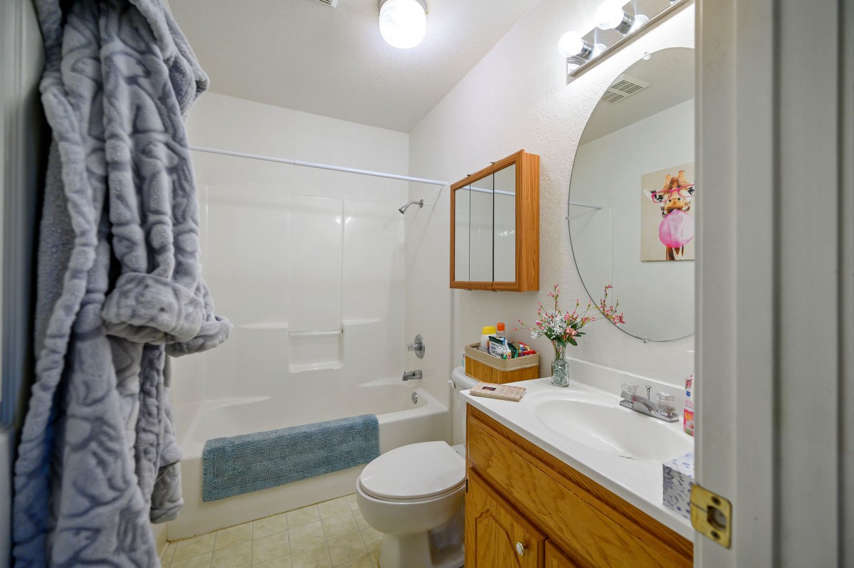 A clean and organized bathroom with a wooden cabinet, shower, and neatly arranged towels.