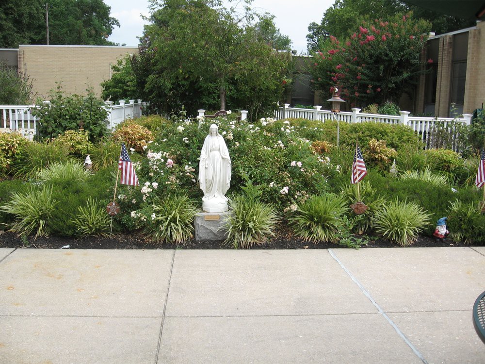 A garden featuring a statue surrounded by flowers and small American flags.