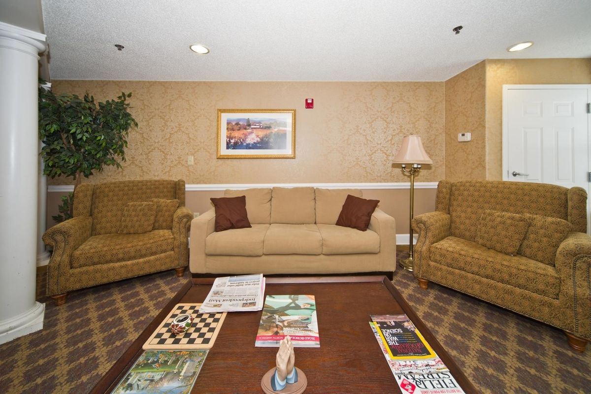 A cozy living room with a central sofa, surrounded by armchairs and a coffee table topped with magazines.