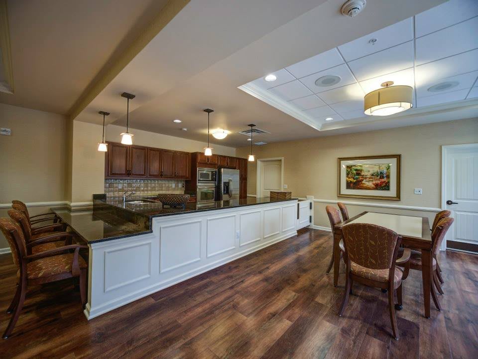 A modern kitchen and dining area with wood flooring and elegant lighting.