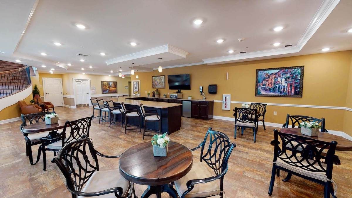 A cozy bar area with seating and modern decor, featuring a television and artwork on the walls.