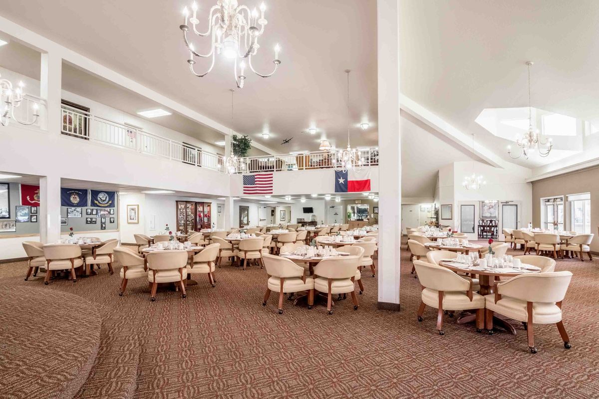 Spacious dining area with chandeliers, tables, and flags on display.