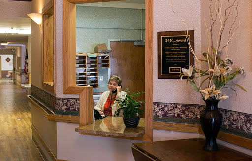A receptionist at an office, engaging on the phone amidst a well-decorated workspace.