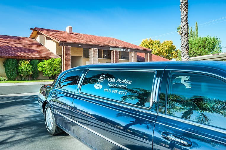 A luxury limousine parked in front of a building on a sunny day.
