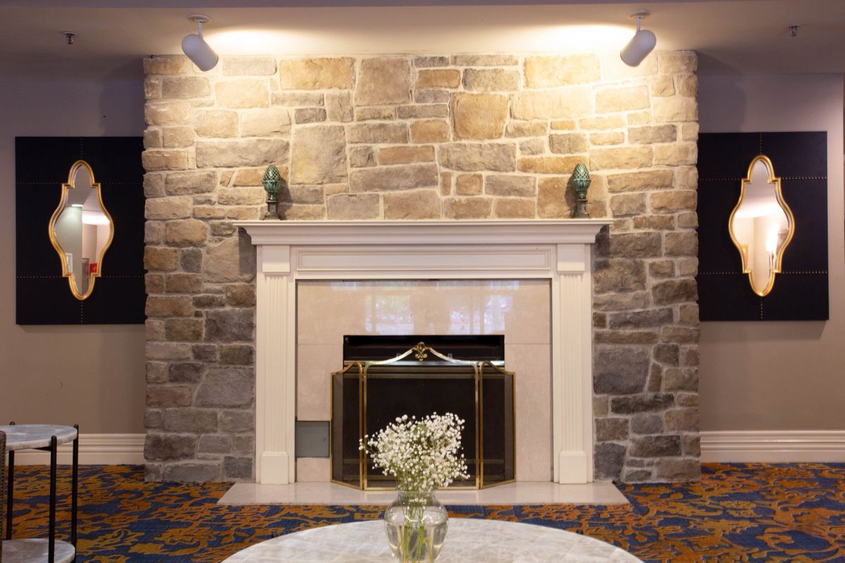 A beautifully designed living room featuring a stone wall and an elegant fireplace.