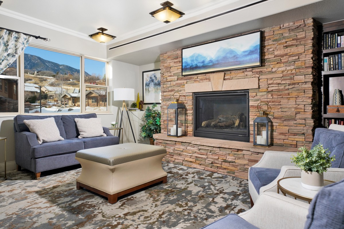 A modern living room featuring a brick fireplace, stylish furniture, and large windows with a scenic view.
