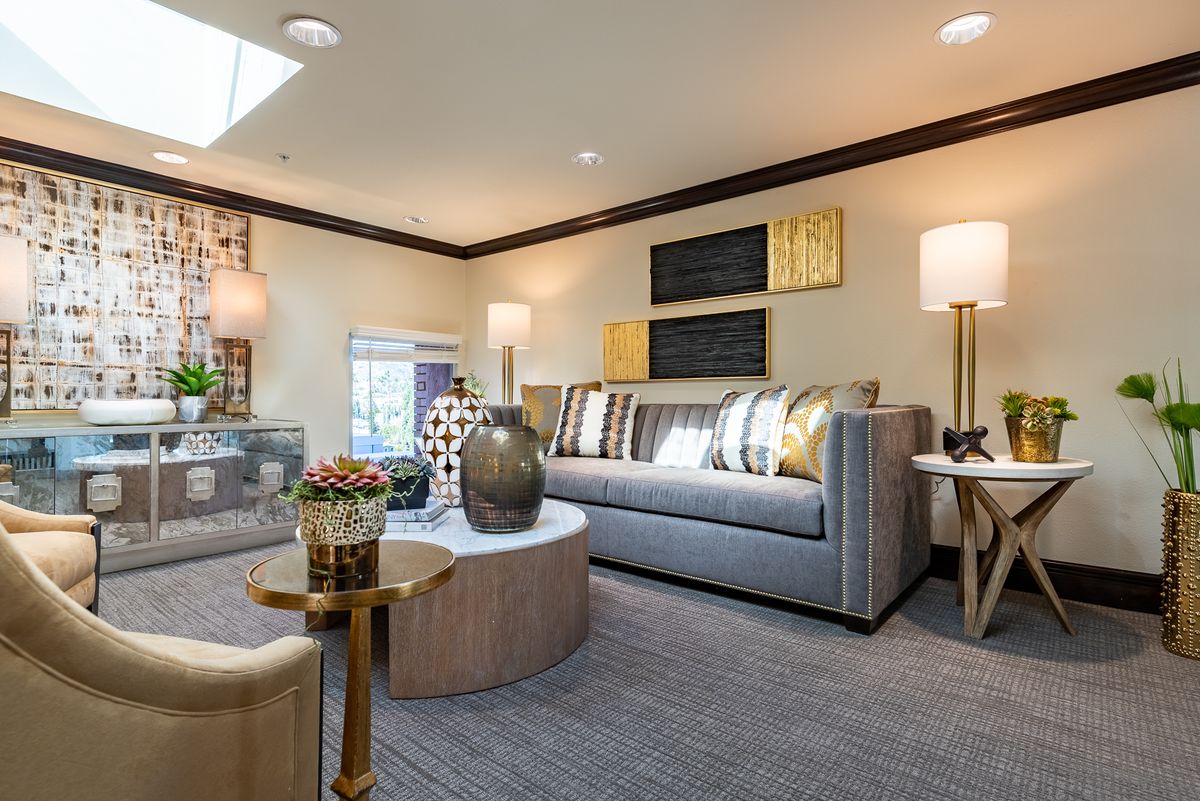 A modern living room featuring a stylish gray sofa, decorative pillows, and elegant lighting with a round coffee table centerpiece.