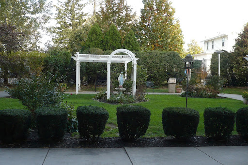 A serene garden featuring a white archway and a central sculpture.