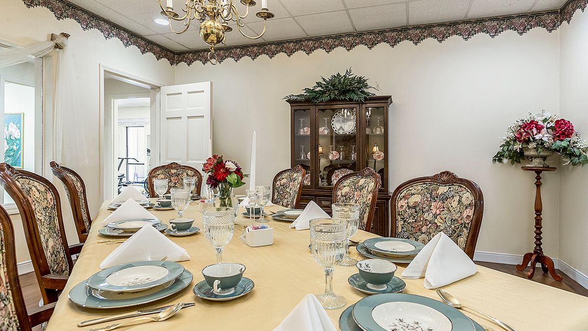 An elegantly set dining room table with fine china and a floral centerpiece.