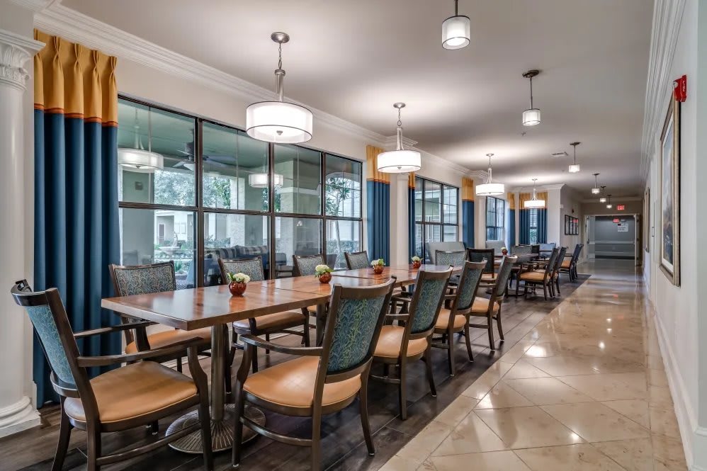 A modern dining area with a long wooden table, surrounded by chairs and illuminated by pendant lights.