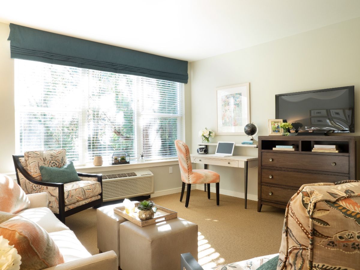 A bright and cozy living room with a large window letting in natural light, featuring comfortable seating and stylish decor.