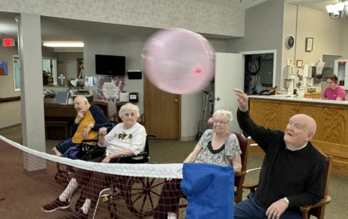 A group of seniors enjoying a balloon activity indoors.