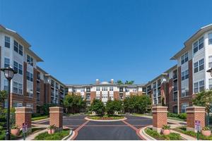 A modern apartment complex with landscaped surroundings under a clear blue sky.