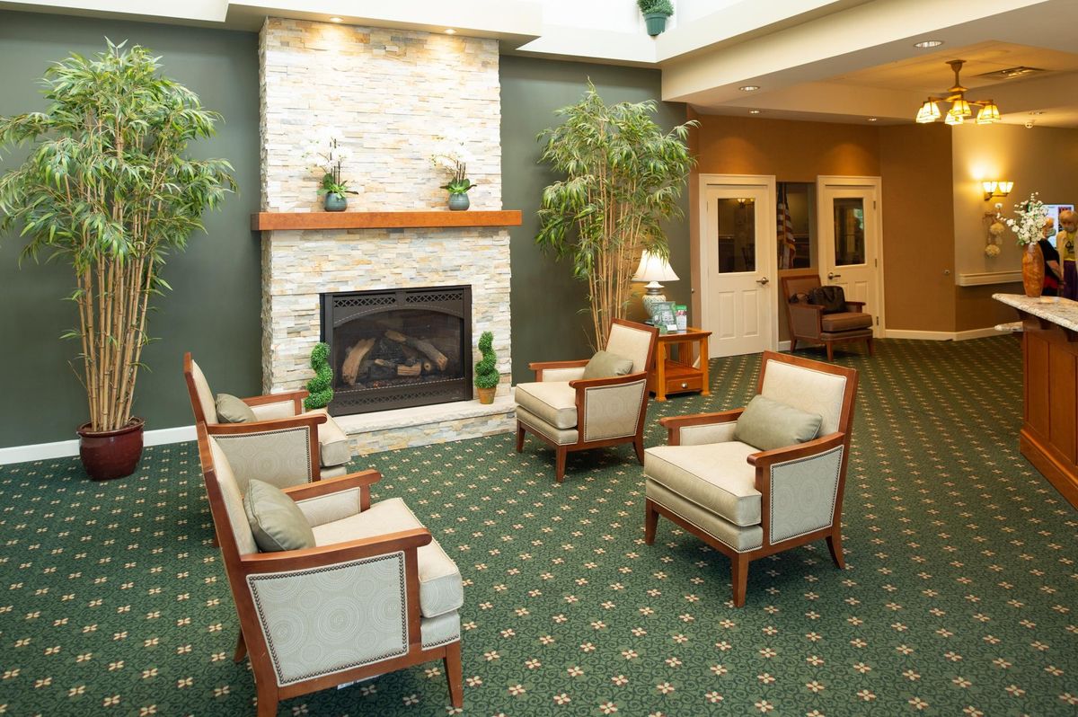 A cozy lobby area featuring a fireplace, comfortable chairs, and indoor plants.