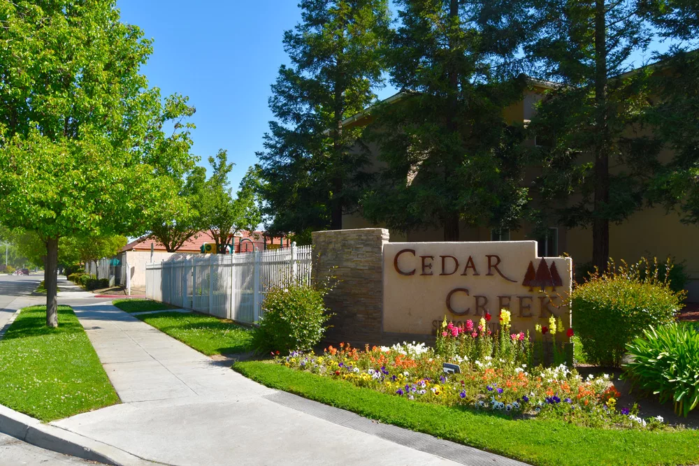 Entrance to Cedar Creek with landscaped path and sign.