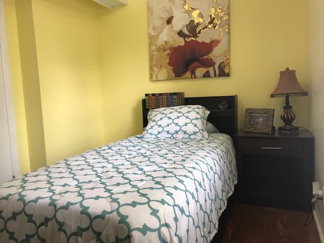 A cozy bedroom with a single bed and colorful artwork on the wall.