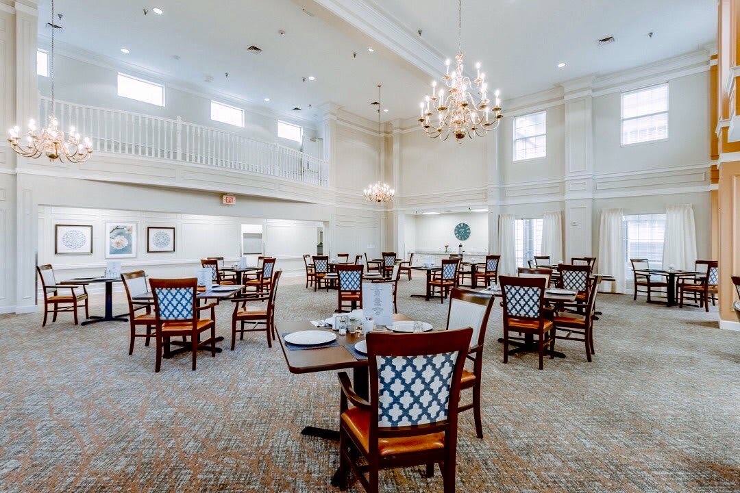 A spacious dining area with neatly arranged tables and chairs under a large chandelier.