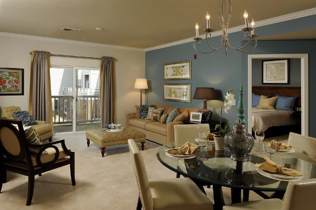 A cozy living room with a blend of elegant furniture, showcasing a chandelier, comfortable sofa, and a dining area.