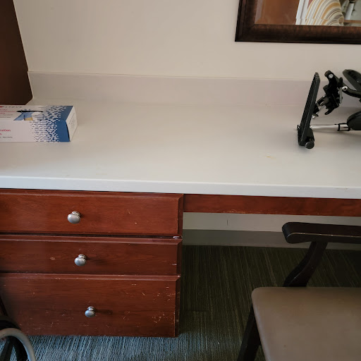 A tidy workspace featuring a wooden desk with three drawers, a chair, and some office supplies.
